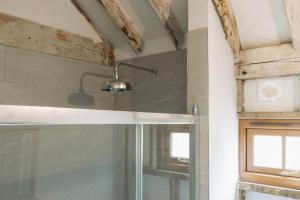 a bathroom with a glass shower and a window at 5 Henham Barns in Beccles