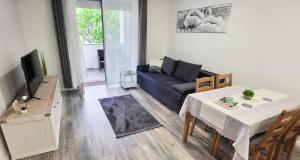 ein Wohnzimmer mit einem blauen Sofa und einem Tisch in der Unterkunft Juhar 1 Apartman in Kőszeg