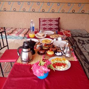 una mesa con un mantel rojo con comida. en Auberge Camping Tafraoute Montagnes, en Tafraoute Sidi Ali