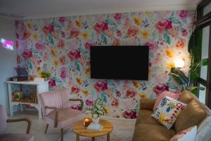 un soggiorno con TV su una parete floreale di Palms on Patti Apartment a Rockhampton