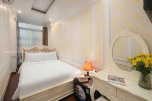 ein Schlafzimmer mit einem großen weißen Bett und einem Spiegel in der Unterkunft The Silk Grand Premium Hotel & Spa in Hanoi