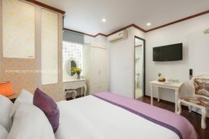 ein Schlafzimmer mit einem großen Bett und einem TV in der Unterkunft The Silk Grand Premium Hotel & Spa in Hanoi