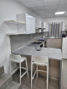a kitchen with a counter and white cabinets and white chairs at Napoli Suites in St. Julianʼs