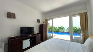 - une chambre avec un lit, une télévision et un balcon dans l'établissement Lumiere Hotel Gili Trawangan, à Gili Trawangan