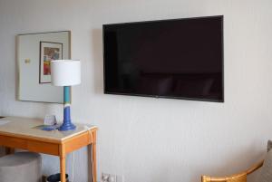 einen Fernseher an einer Wand mit einer Lampe auf einem Tisch in der Unterkunft Coral Beach Hotel & Resort Cyprus in Coral Bay