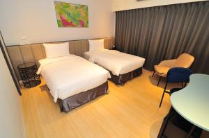 a hotel room with two beds and a table and chair at Hotel Lounge in Toucheng