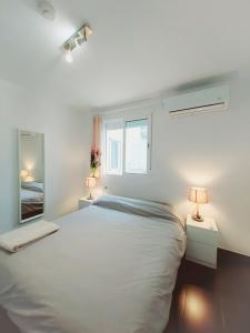 Habitación blanca con cama y espejo en Alojamiento Amelie con WiFi gratis, en Murcia