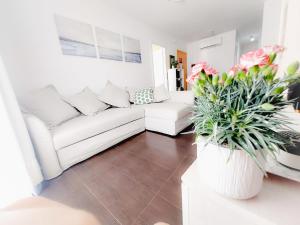een woonkamer met een witte bank en bloemen bij Alojamiento Amelie con WiFi gratis in Murcia
