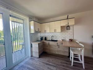 a kitchen with a counter and a table with a chair at Rabbit 2 Apartman in Mosonmagyaróvár +9 photos