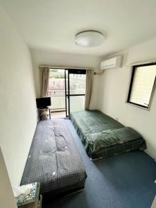 Habitación pequeña con 2 camas y ventana en Hana House West Shinjuku, en Tokio