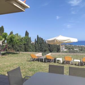 un grupo de sillas, una sombrilla y una mesa en Sea Breeze Villa, en Rethymno