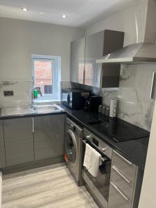 een keuken met een wastafel en een wasmachine bij HOMESTAY HAVEN in Leicester