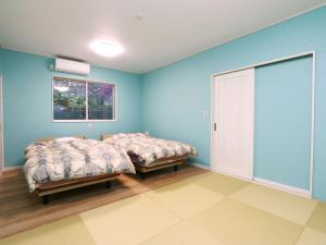 2 camas en una habitación con paredes azules en 神津島民宿菊乃屋～きくのや～kikunoya, en Kōzushima