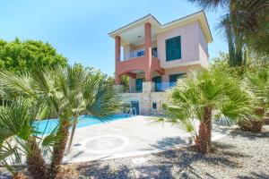 ein Haus mit Palmen vor einem Pool in der Unterkunft Amorosa Beach Villa 6 in Neo Chorio
