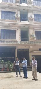 Old Everest Hotel في Khanchikot: ثلاث رجال واقفين امام مبنى
