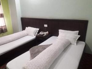 Old Everest Hotel في Khanchikot: سريرين في غرفة الفندق عليها هاتف