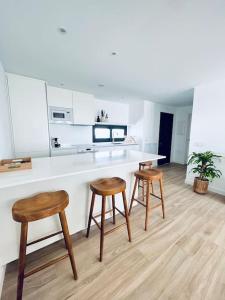 a kitchen with two stools and a white counter top at Apartamento Fuerteventura in Villaverde +16 photos