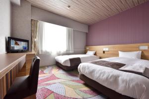 釧路市にあるスマイルホテル釧路のベッド2台とテレビが備わるホテルルームです。