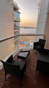 Un balcón con sillas y mesas en un edificio en شقة غرفتين وصاله مطله على البحر برج ابحر ريزيدنس 1 en Obhor
