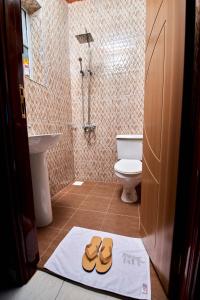 bagno con servizi igienici e un paio di sandali sul pavimento di PB & J Guest House Entebbe a Entebbe