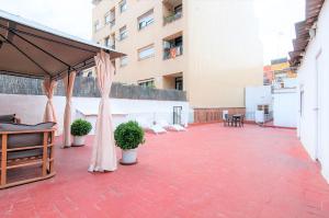 un patio con plantas y sombrillas en un edificio en Pintor Pahissa Rooms, en Barcelona