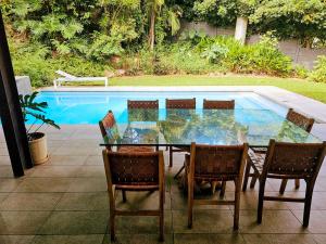 une table et des chaises en verre à côté de la piscine dans l'établissement Umhlanga Lodge, à Durban