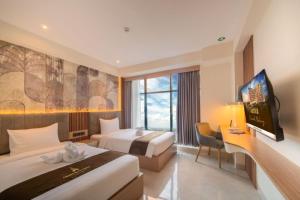 a hotel room with two beds and a flat screen tv at Grand Altuz Hotel Yogyakarta in Seturan