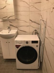 eine weiße Waschmaschine im Bad mit Waschbecken in der Unterkunft AUDRU APARTMENT Newly renovated apartment with SAUNA, near Audru Golf in Audru