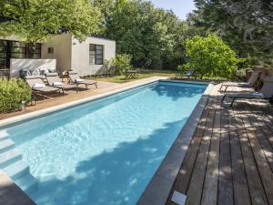 a swimming pool with a wooden deck and chairs around it at Holiday Home Villa Isabelle by Interhome in Gondonnets