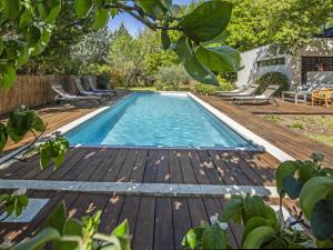 a swimming pool on a wooden deck with chairs around it at Holiday Home Villa Isabelle by Interhome in Gondonnets