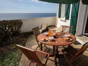 een houten tafel en stoelen op een patio met uitzicht op de oceaan bij Holiday Home Les Roches - LPU 103 by Interhome in Clohars-Carnoët