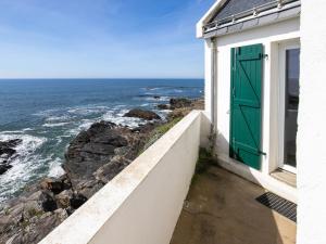 une maison blanche avec une porte verte et l'océan dans l'établissement Holiday Home Les Roches - LPU 103 by Interhome, à Clohars-Carnoët