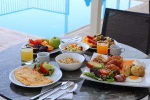 a table with plates of breakfast foods and drinks at Queens Bay Hotel in Paphos