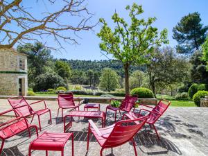 un groupe de chaises et de tables rouges dans une cour dans l'établissement Holiday Home Domaine de Piegros by Interhome, à La Bastide-des-Jourdans