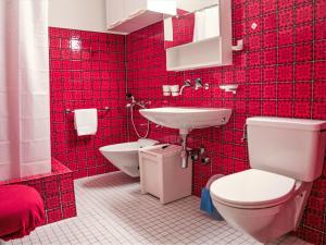 a red tiled bathroom with a toilet and a sink at Apartment Residenz Surlej 6 by Interhome in St. Moritz