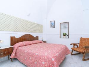 a bedroom with a bed with a red comforter and a chair at Apartment Limoneto a Priora by Interhome in Massa Lubrense