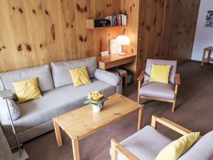 een woonkamer met een bank, 2 stoelen en een tafel bij Apartment Utoring Acletta-105 by Interhome in Disentis