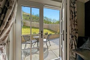 una porta che conduce a un patio con tavolo e sedie di Outlander Glencoe at Creag an-t Sionnaich a Glencoe