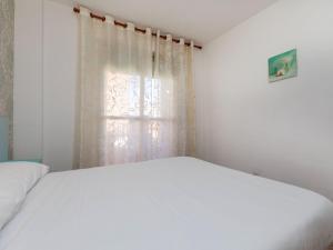 1 dormitorio con cama blanca y ventana en Apartment Las Americas by Interhome, en Lloret de Mar
