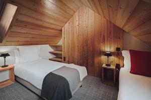 ル・モネティエ・レ・バンにあるAlliey & Spa Piscine Appart-hôtel Serre chevalierの木製の壁のベッドルーム1室(ベッド2台付)