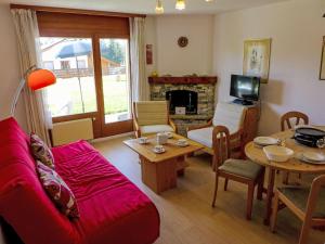 a living room with a red couch and a table at Apartment Santa Barbara by Interhome in Crans-Montana