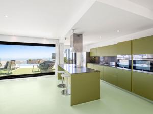 a kitchen with green cabinets and a large window at Villa Megin by Interhome in Cumbre del Sol