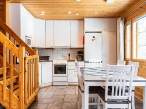 ユッラスヤルヴィにあるHoliday Home Kultapiisku 2 by Interhomeの白いキャビネット、テーブルと椅子付きのキッチンが備わります。