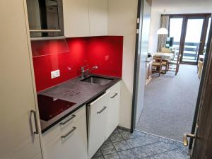 uma cozinha com um lavatório e uma parede vermelha em Apartment Utoring Acletta-9 by Interhome em Disentis