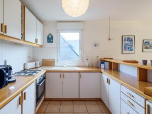 KernalléguenにあるHoliday Home Maison bleue by Interhomeの白いキャビネットと窓付きのキッチン