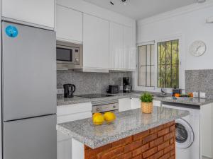 una cocina con electrodomésticos blancos y un bol de fruta en una barra en Apartment Las Farolas family retreat by Interhome, en Mijas Costa
