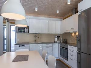 a kitchen with white cabinets and a table with chairs at Holiday Home Villa ukkohalla by Interhome in Ukkohalla