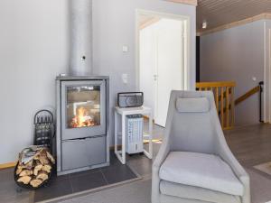 a living room with a fireplace and a chair at Holiday Home Villa ukkohalla by Interhome in Ukkohalla