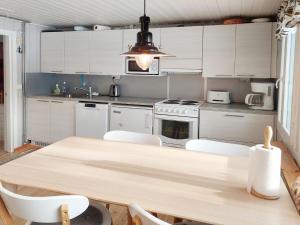 cocina con mesa de madera y armarios blancos en Holiday Home Mukan maja by Interhome, en Köngäs