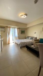 a bedroom with a bed and a table and a couch at Condo Unit near Ayala Serin Mall in Tagaytay